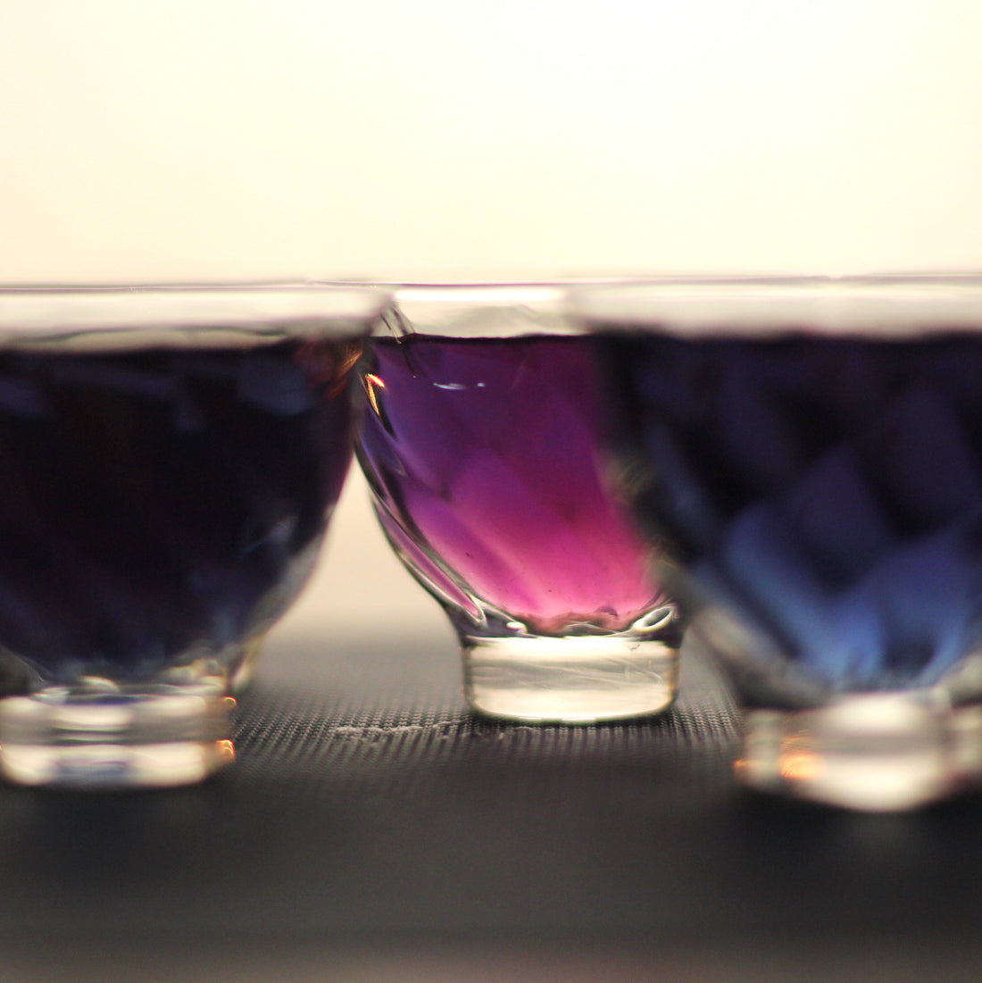 Three glass cups with different coloured tea infusions showing variation in flavour and oxidation