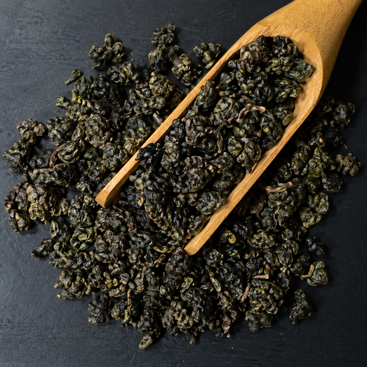 Loose leaf Gaba oolong tea in a wooden scoop on dark background