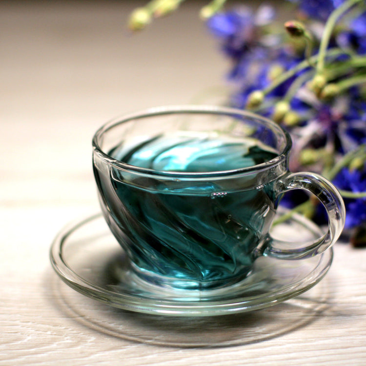 Vibrant blue flavoured tea in a glass cup with a clear, elegant infusion